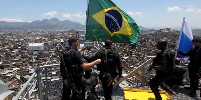 Policemen place a Brazilian flag at a top point of the Complexo do Alemao slum in Rio de Janeiro, Brazil, Sunday, Nov. 28, 2010. Rio's most dangerous slum that was the backbone of the city's biggest drug gang was taken by 2,600 police and soldiers Sunday, an unprecedented accomplishment by authorities in their fight to secure this seaside metropolis that will host the 2016 Olympics. (AP Photo/Silvia Izquierdo)