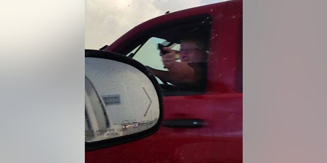 A woman identified as Amanda Downs points a folding knife cast to resemble a gun at fellow motorist in La Porte, Texas August 2.
