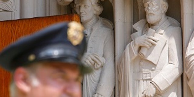 A Duke University security guard keeps watch near the defaced statue of Confederate commander General Robert E. Lee, which stands next to a statue of Thomas Jefferson, at Duke Chapel in Durham, North Carolina, U.S. on August 17, 2017. REUTERS/Jonathan Drake - RTS1C7L2