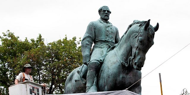 City workers drape a tarp over the statue of Confederate General Robert E. Lee in Emancipation park in Charlottesville, Va., Wednesday, Aug. 23, 2017. 