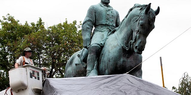 City workers drape a tarp over the statue of Confederate General Robert E. Lee in Emancipation park in Charlottesville, Va., Wednesday, Aug. 23, 2017. The move intended to symbolize the city's mourning for Heather Heyer, killed while protesting a white nationalist rally earlier this month. (AP Photo/Steve Helber)