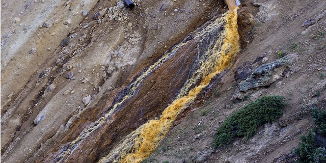 FILE--In this Aug. 13, 2015, file photo, wastewater flows from a trough and down a steep ravine at the site of the blowout at the Gold King mine which triggered a major spill of toxic wastewater, outside Silverton, Colo.Crumbling mine tunnels awash with polluted waters perforate the Colorado mountains, and scientists may one day send robots creeping through the pitch-black passages to study the mysterious currents that sometimes burst to the surface with devastating effects. (AP Photo/Brennan Linsley)