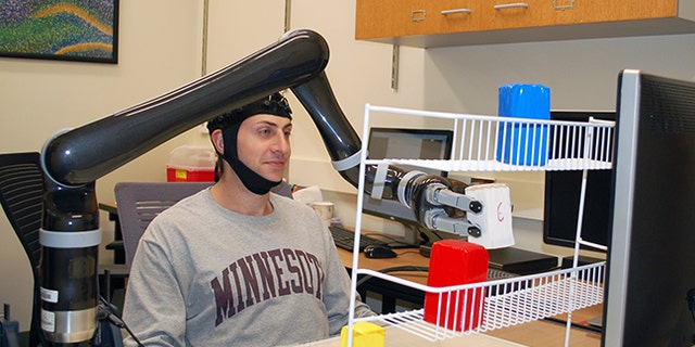 Research subjects at the University of Minnesota fitted with a specialized noninvasive brain cap were able to move the robotic arm just by imagining moving their own arms.
