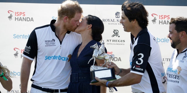 While Prince Harry was being presented his polo-winning trophy, he appeared to be a bit distracted by his wife.