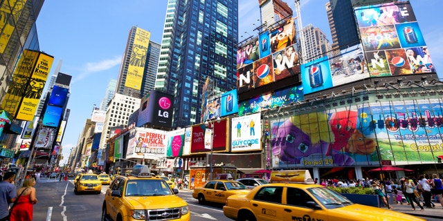 NEW YORK CITY - CIRCA JULY 2012: Yellow taxi cabs crossing Times Square with crowds of people and lots of advertising on July, 2012 in Manhattan, New York City. USA