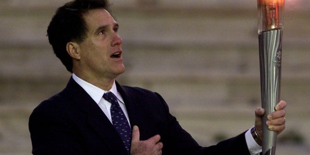 President of the organising committee of Salt Lake Winter Olympic Games Mitt Romney sings U.S. national anthem as he raises an Olympic torch during a handing-over ceremony in Athens' Panathenean stadium.