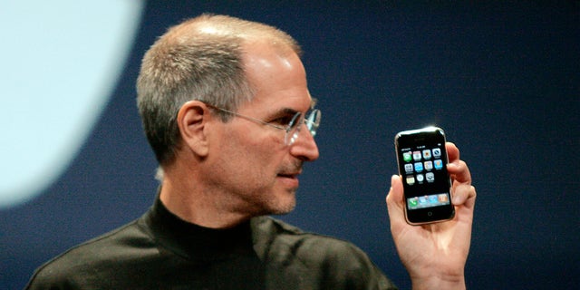 Steve Jobs, then CEO of Apple, holds an iPhone in San Francisco, California, on January 9, 2007. 