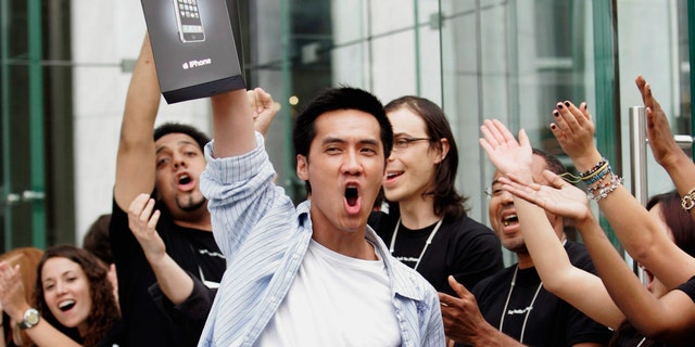Surrounded by Apple Store employees, an early iPhone buyer leaves the store on Fifth Avenue in Manhattan on June 29, 2007. 