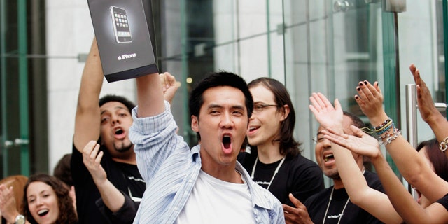 Surrounded by Apple Store employees, an early iPhone buyer leaves the store on Fifth Avenue in Manhattan on June 29, 2007.