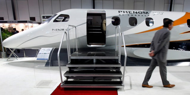 A man walks past a replica of Embraer's Phenom 300 jet at the "Extravaganza 2008 Show" in Mumbai February 23, 2008.