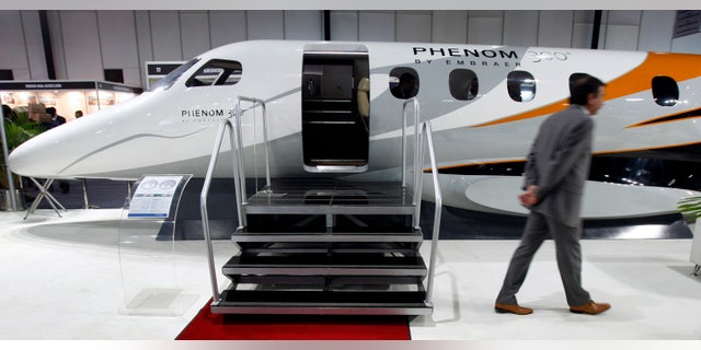 A man walks past a replica of Embraer's Phenom 300 jet at the "Extravaganza 2008 Show" in Mumbai February 23, 2008.