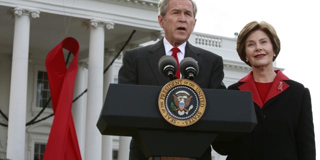 FILE -- Former President George W. Bush speaks alongside a giant red AIDS ribbon on the occasion of World AIDS day with first lady Laura Bush on the North Lawn of the White House in Washington December 1, 2008.