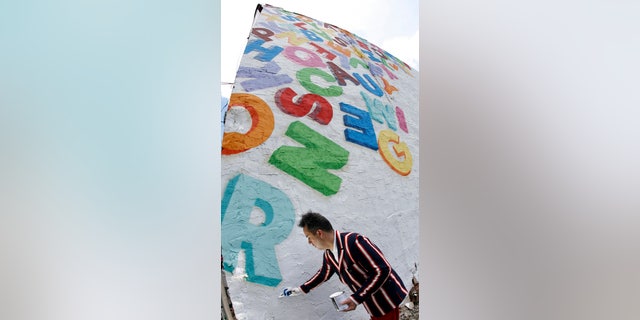Artist Stephen Powers touches up a mural which is part of the "Love Letters " 50 mural project in Philadelphia, Pennsylvania, July 8, 2009. On the side of a West Philadelphia barber shop, a painted jumble of multicolored letters and a few words mark the start of a massive mural project to celebrate community in one of the city's poorest neighborhoods. REUTERS/Tim Shaffer (UNITED STATES SOCIETY ENTERTAINMENT) - RTR25I0S