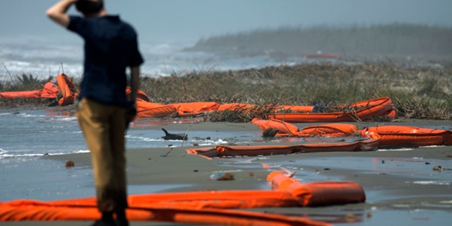 May 2, 2010: A television reporter stands beside oil booms at the coast of South Pass, south of Venice, Louisiana, as oil leaking from the Deepwater Horizon wellhead continues to spread in the Gulf of Mexico.