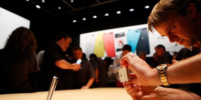 Members of the media photograph the iPhone 5 after its introduction during Apple Inc.'s iPhone media event in San Francisco, California, Sept. 12, 2012.