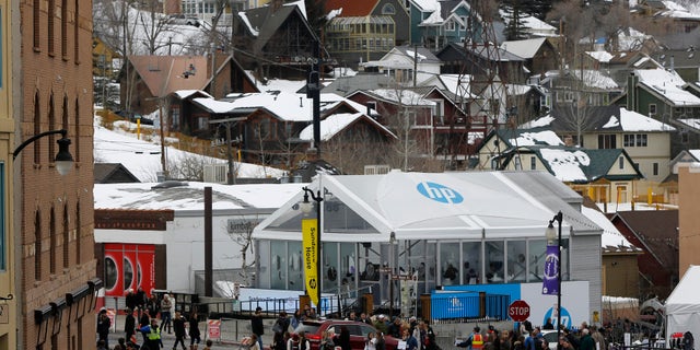 Pedestrians cross the street near skiers on a lift during Sundance Film Festival in Park City, Utah, January 24, 2015.