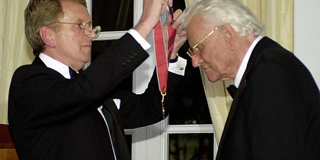 Billy Graham receives a medal as he is presented with an honorary knighthood by British Ambassador Sir Christopher Meyer in a ceremony at the British Embassy, December 6, 2001 in Washington. Graham was recognized for his contribution to civic and religious life for over sixty years, having preached the gospel to more people in live audiences than anyone in history.