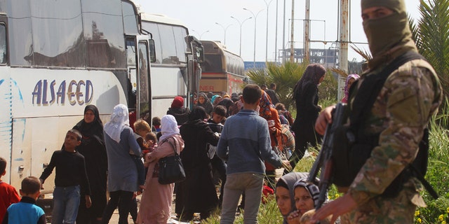 A rebel fighter stands near buses carrying people that were evacuated from the two villages of Kefraya and al-Foua, after a stall in an agreement between rebels and Syria's army, at insurgent-held al-Rashideen, Aleppo province, Syria April 15, 2017. REUTERS/Ammar Abdullah - RTS12EFB