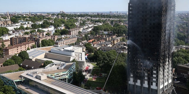 A firefighter directs a jet of water at a tower block severely damaged by a serious fire, in north Kensington, West London, Britain June 14, 2017. REUTERS/Neil Hall - RTS172ZC