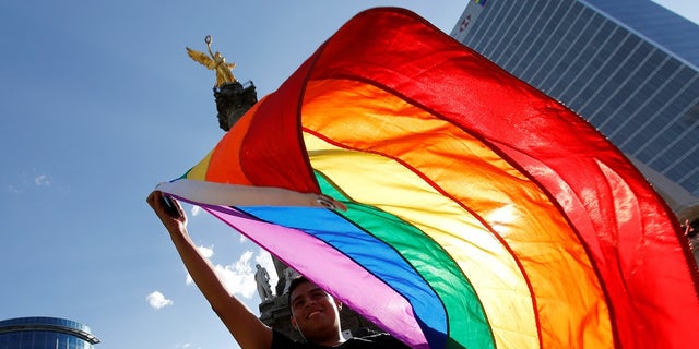 A member of the LGBT community, holds up a rainbow flag during a protest against the constant discrimination and violence against their community, at the Angel of Independence monument in Mexico City, Mexico June 23, 2017