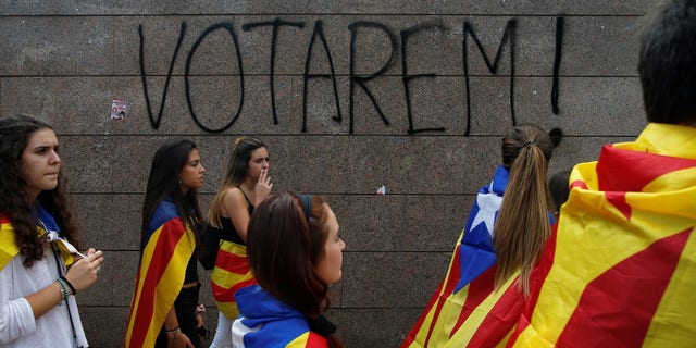 Students wear Esteladas (Catalan separatist flag) during a demonstration in favor of the banned October 1 independence referendum in Barcelona, Spain. The graffiti on the wall reads, "We will vote!"