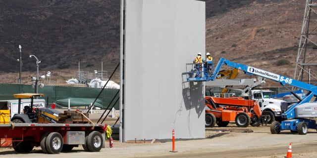 People work in San Diego at the construction site of prototypes for President Trump's border wall with Mexico, in this picture taken from the Mexican side of the border in Tijuana.