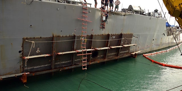 In this October 5, 2017 photo, a temporary patch is welded to the area damaged by a collision aboard USS John S. McCain.