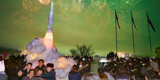 North Koreans pose in front of ICBM Hwasong-15 ice sculpture during New Year's Day celebration