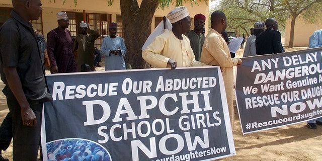 People carry banners during the visit of Nigeria's President Muhammadu Buhari in Dapchi.