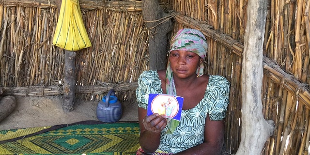 The mother of one of the abducted girls holds up a photo.