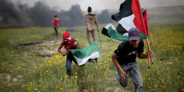 Palestinian demonstrators run during clashes with Israeli troops near the border with Israel, in the southern Gaza Strip March 23, 2018.