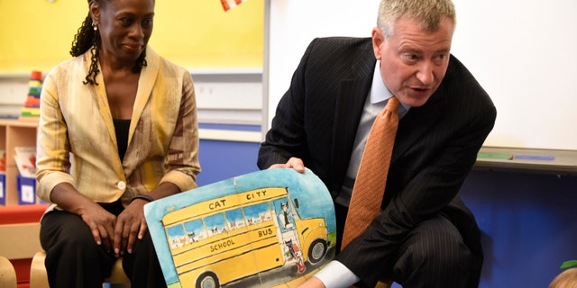 New York City Mayor Bill de Blasio (R) reads a book to pre-K students on their first day of school at Public School 59 in Staten Island, New York, September 9, 2015. At left is First Lady Chirlane McCray. REUTERS/Barry Williams/Pool