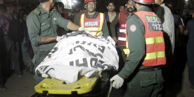 Rescue workers move a body from the site of a blast in Pakistan.