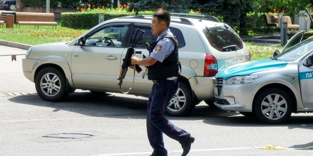 A policeman runs across the street in Almaty, Kazakhstan Monday.