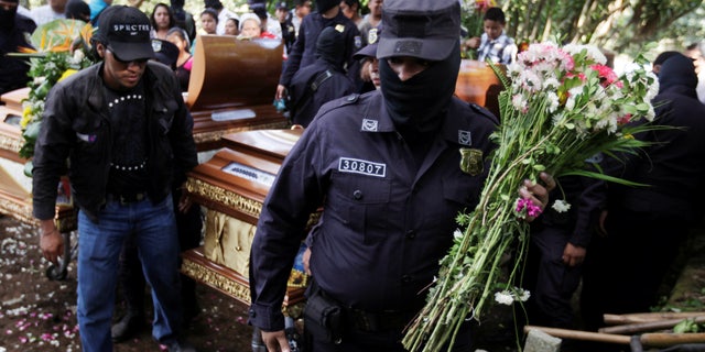 Salvadoran police officers participate in the funeral ceremony for their colleague Lorenzo Rojas Herrera and his son Marvin, who were killed by suspected gang members.