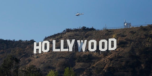 A Los Angeles Police Department (LAPD) helicopter flies over the Hollywood sign in Hollywood, California February 21, 2014. To match TRAVEL-HOLYWOOD  REUTERS/Mario Anzuoni  (UNITED STATES - Tags: ENTERTAINMENT ENVIRONMENT SOCIETY TRAVEL) - RTX19A0U