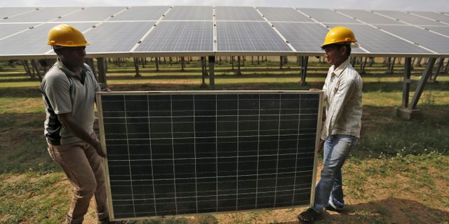 Workers carry a damaged photovoltaic panel inside a solar power plant in Gujarat, India, July 2, 2015. India's $100 billion push into solar energy over the next decade will be driven by foreign players as uncompetitive local manufacturers fall by the wayside, no longer protected by government restrictions on the sector. REUTERS/Amit Dave - RTX1IR4N