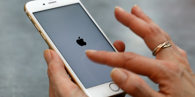 A woman uses her mobile phone, an iPhone 6 by Apple in Munich downtown, Germany, January 27, 2016.