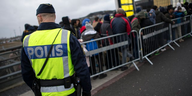 A police officer keeps guard as migrants arrive at Hyllie station outside Malmo, Sweden. Picture taken November 19, 2015. REUTERS/Johan Nilsson/TT NEWS AGENCY ATTENTION EDITORS - THIS IMAGE WAS PROVIDED BY A THIRD PARTY. FOR EDITORIAL USE ONLY. NOT FOR SALE FOR MARKETING OR ADVERTISING CAMPAIGNS. THIS PICTURE IS DISTRIBUTED EXACTLY AS RECEIVED BY REUTERS, AS A SERVICE TO CLIENTS. SWEDEN OUT. NO COMMERCIAL OR EDITORIAL SALES IN SWEDEN. NO COMMERCIAL SALES. - RTX24DEM