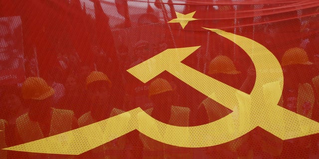 FILE - -People walk behind a red banner with hammer and sickle symbols during a May Day rally on May 1, 2016 in Istanbul, Turkey.
