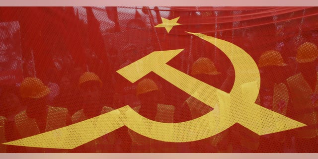 FILE - -People walk behind a red banner with hammer and sickle symbols during a May Day rally in Istanbul, Turkey, May 1, 2016.