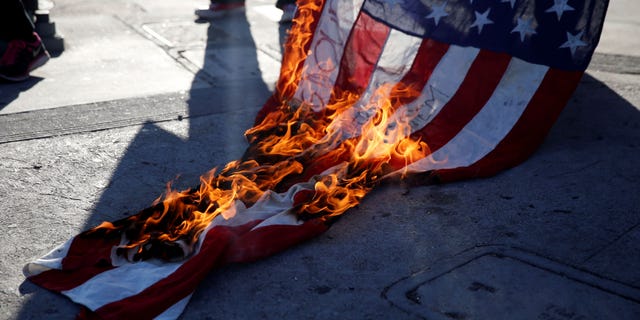 Activists burn a flag while protest on the corner of Florence Ave and Normandie Ave against the police shootings that lead to two deaths in Louisiana and Minnesota, respectively, in Los Angeles, California, U.S. July 7, 2016. REUTERS/Patrick T. Fallon - RTX2K9GY