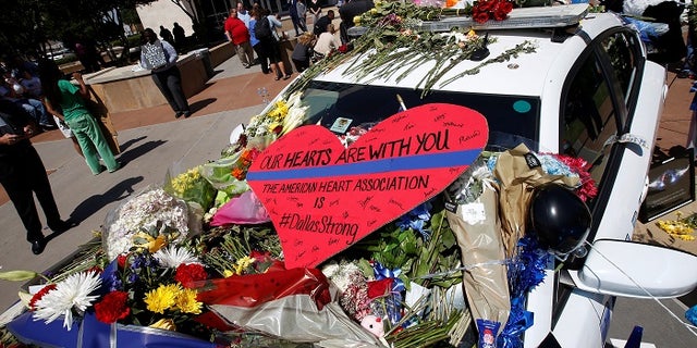 A heart is pictured on a police car that makes up part of a makeshift memorial at Police Headquarters following the multiple police shooting in Dallas, Texas, U.S.,July 8, 2016. REUTERS/Carlo Allegri - RTX2KEUZ