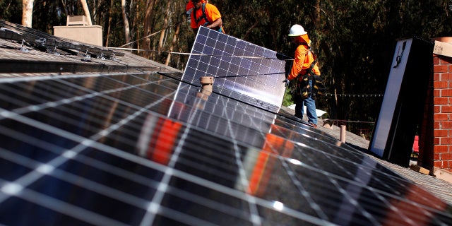 Solar installers from Baker Electric place solar panels on the roof of a residential home in Scripps Ranch, San Diego, Calif., Oct. 14, 2016.
