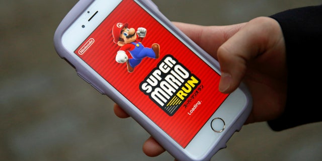 Takuya Nishya shows Nintendo's "Super Mario Run" game on his smartphone by the request of a photographer in Tokyo, Japan, December 20, 2016. (REUTERS/Kim Kyung-Hoon)