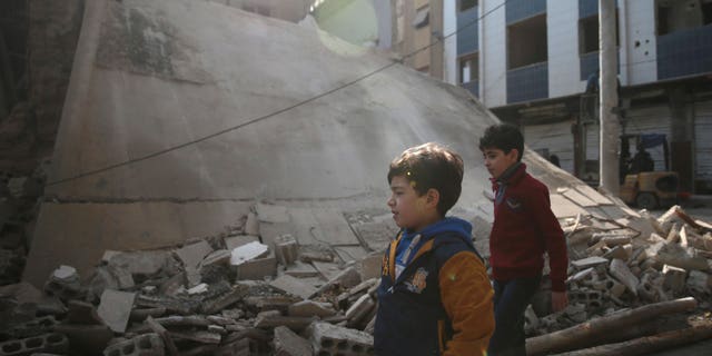 Boys walk near a damaged building in the rebel held besieged city of Douma, in the eastern Damascus suburb of Ghouta, Syria December 30, 2016. REUTERS/Bassam Khabieh - RTX2WYAO