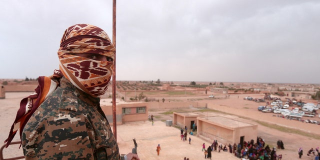 A Syrian Democratic Forces (SDF) fighter overlooks people fleeing areas surrounding Euphrates River dam, east of Raqqa city, Syria March 30, 2017. REUTERS/Rodi Said - RTX33FPL