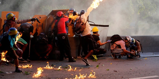 An opposition supporter throws a petrol bomb while clashing with riot security forces during a rally against President Nicolas Maduro in Caracas, Venezuela, May 18, 2017. REUTERS/Marco Bello - RTX36IDB