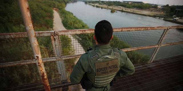 A U.S. Border Patrol agent looks over the Rio Grande River at the border between the U.S. and Mexico in Roma, Texas.
