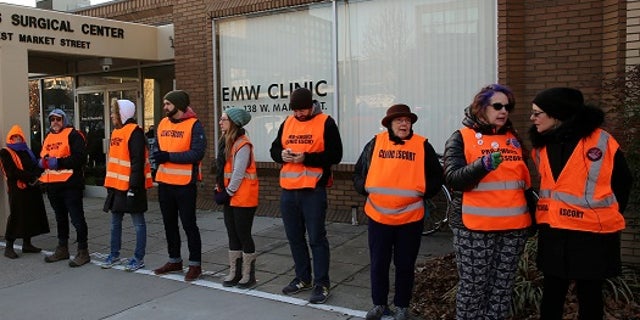 Escorts stand outside of EMW Women's Surgical Center in Louisville, Ky., the last abortion clinic in the state. The center is embroiled in a legal battle with the state over requirements to stay open.